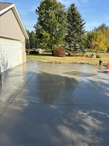 A concrete driveway leading to a garage with trees in the background.