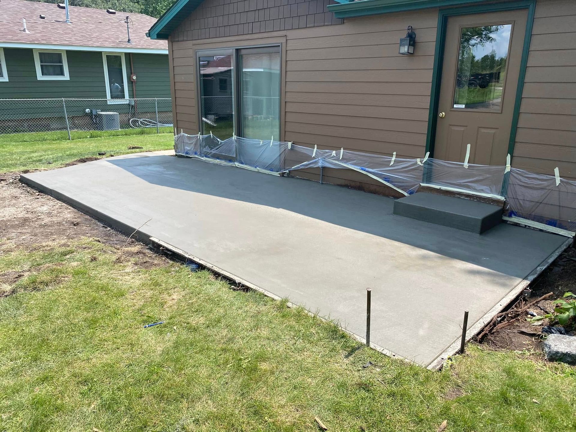 A concrete patio is being built in front of a house.