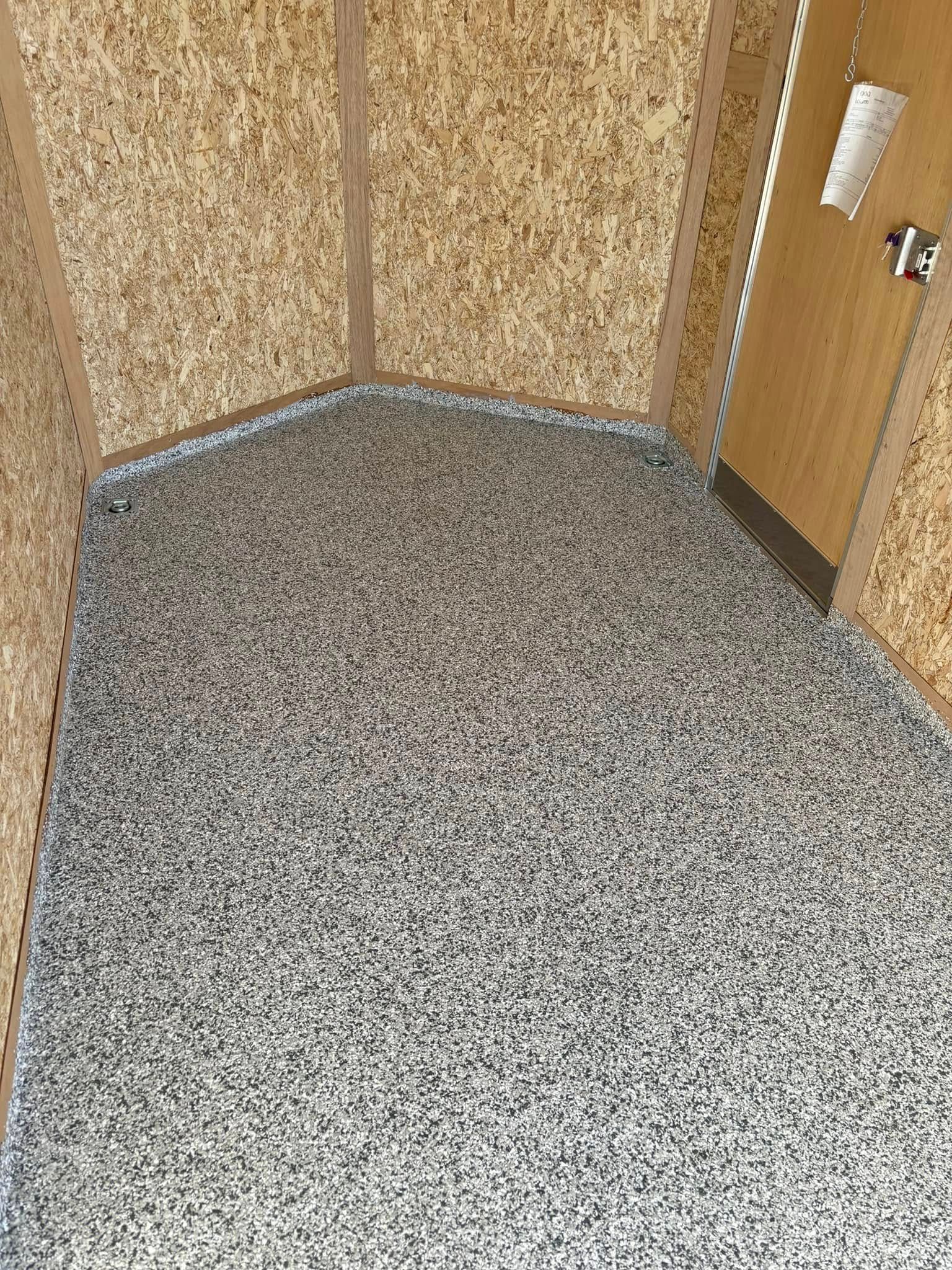 A room with a gray floor and a door.