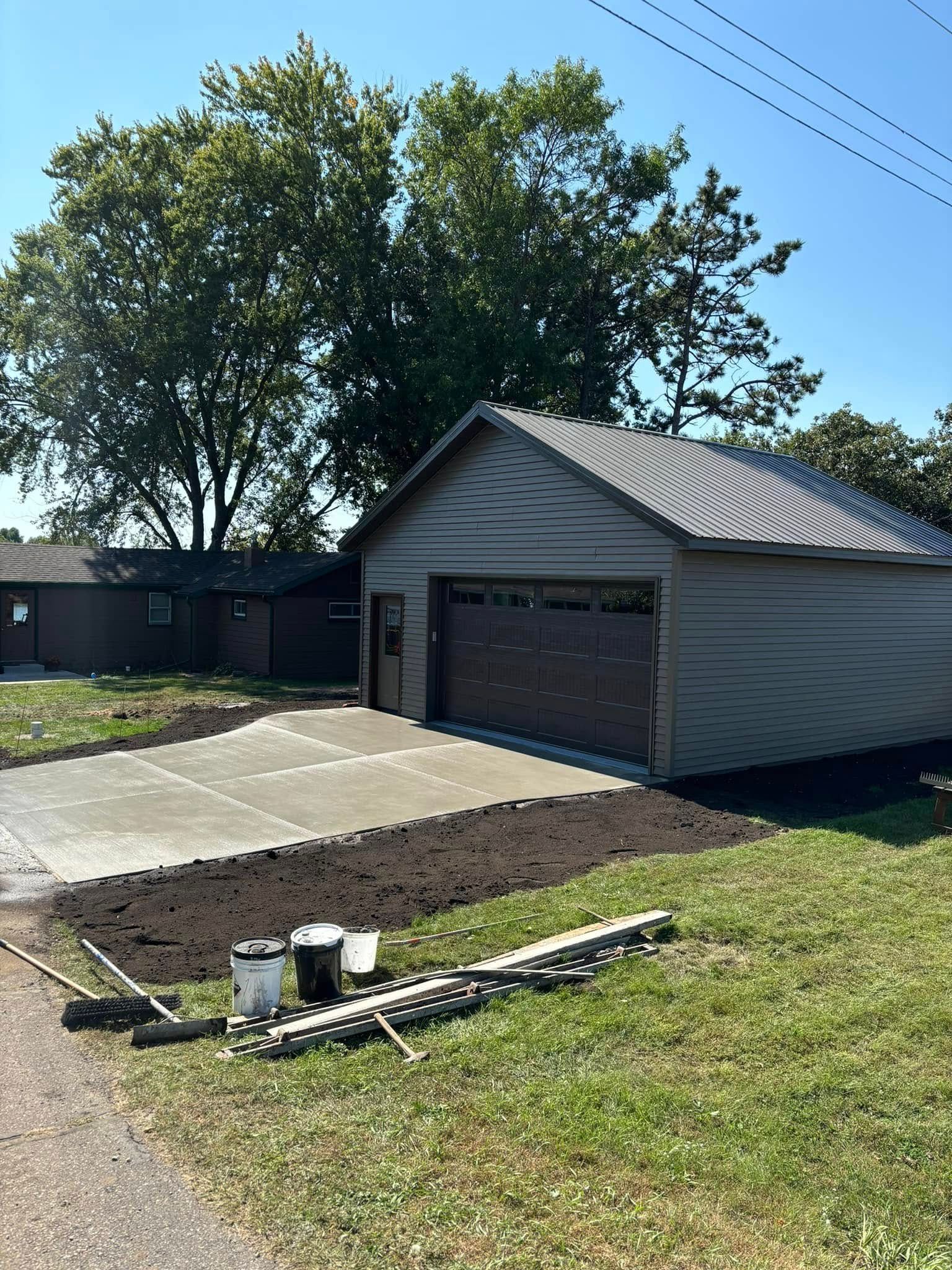 A garage with a concrete driveway in front of it.