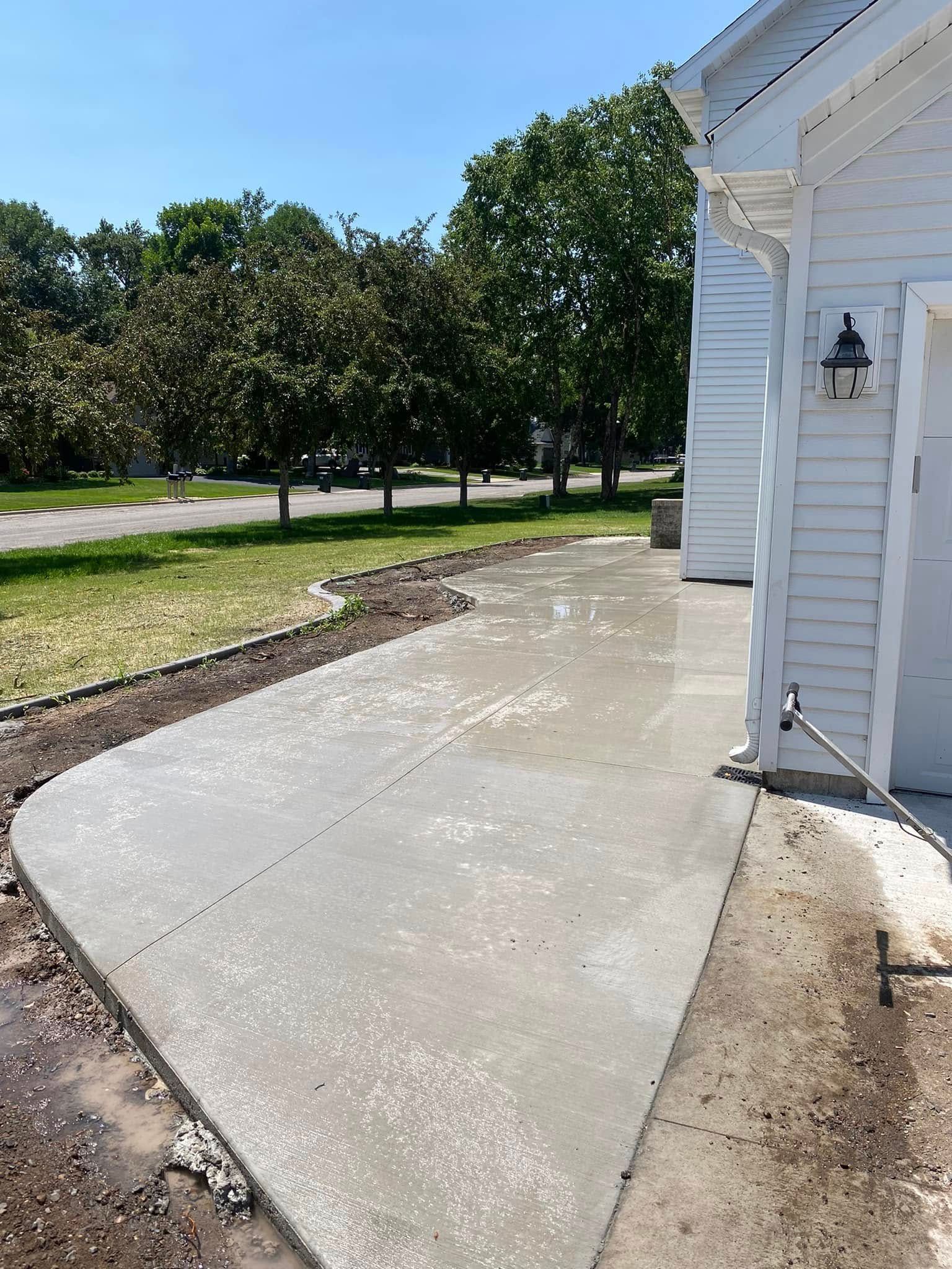 A concrete driveway is being built in front of a white house.