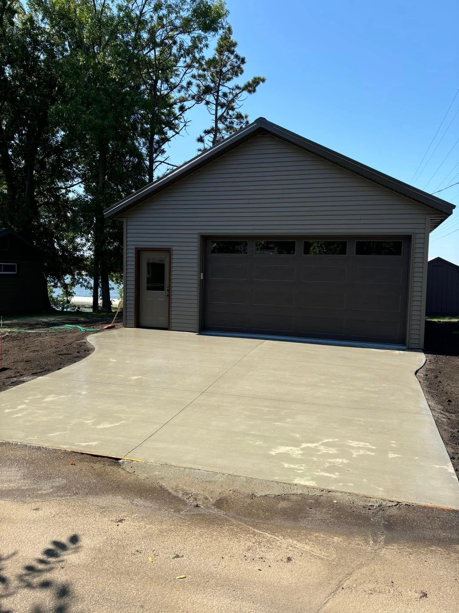 A garage with a concrete driveway in front of it