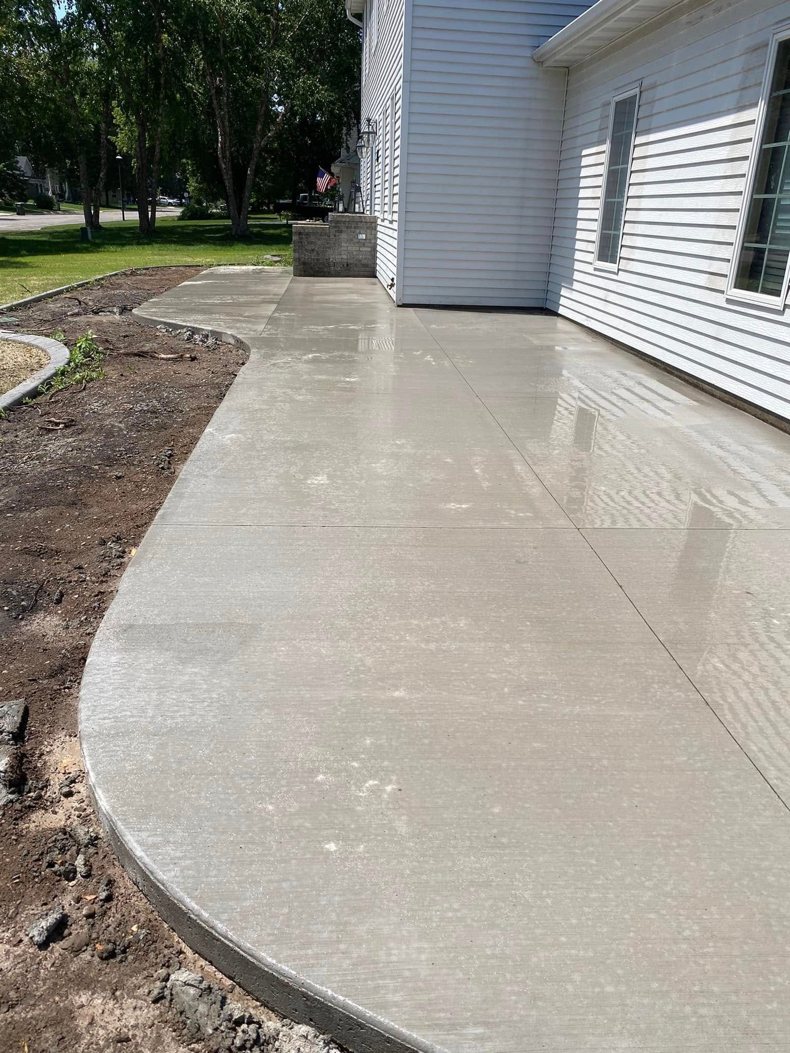 A concrete walkway is being built in front of a white house.