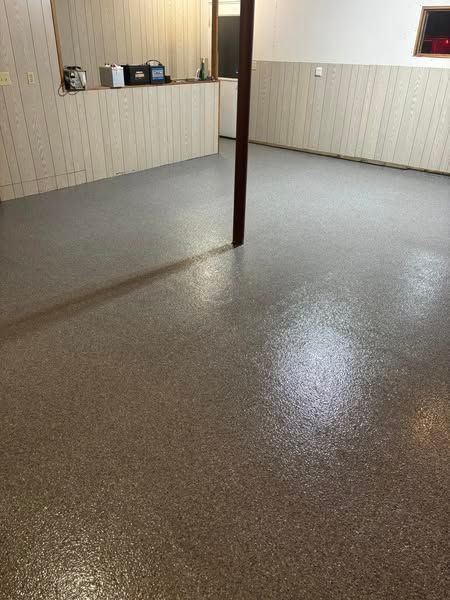 A room with a concrete floor and a wooden wall.