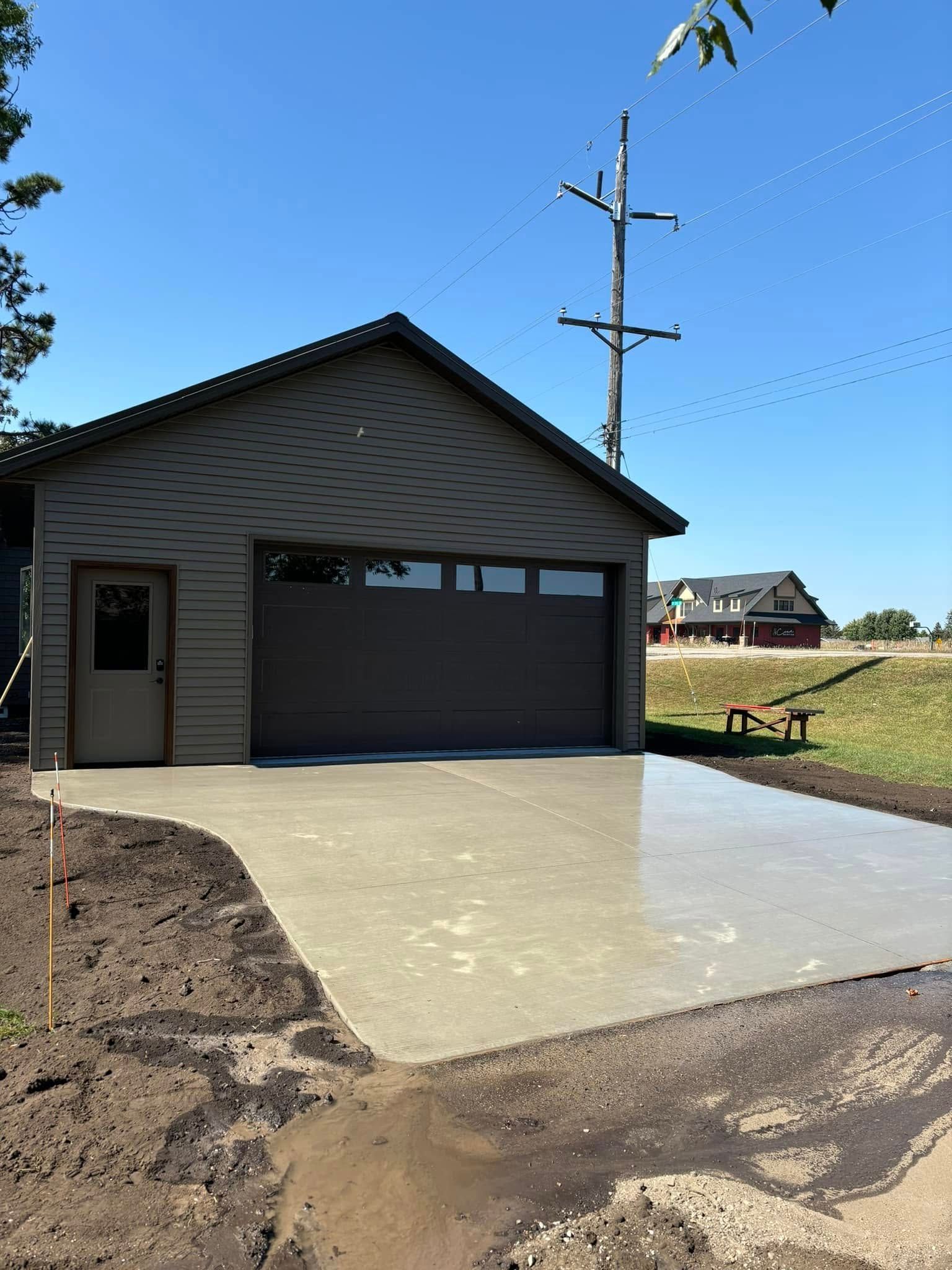 A garage with a concrete driveway in front of it.