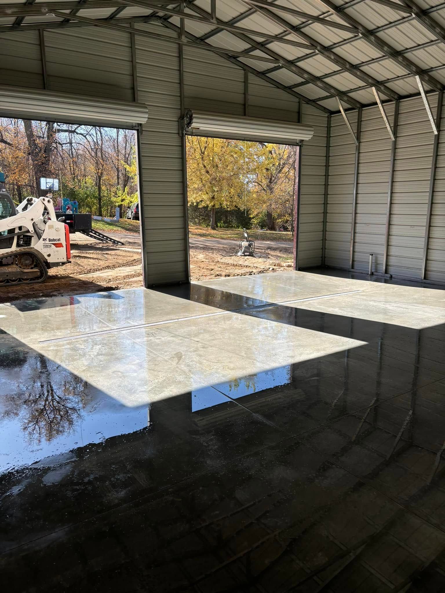 A large garage with a concrete floor and a reflection of a bulldozer in the floor.
