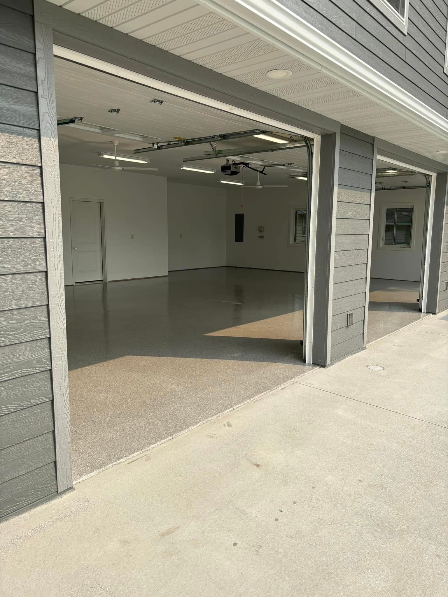 A garage with the doors open and a concrete floor.