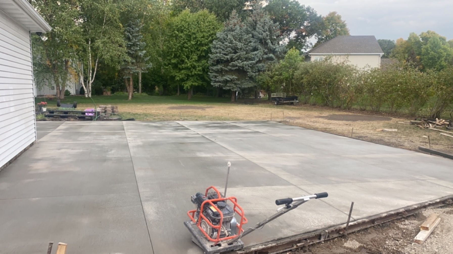 A concrete driveway is being built in the backyard of a house.
