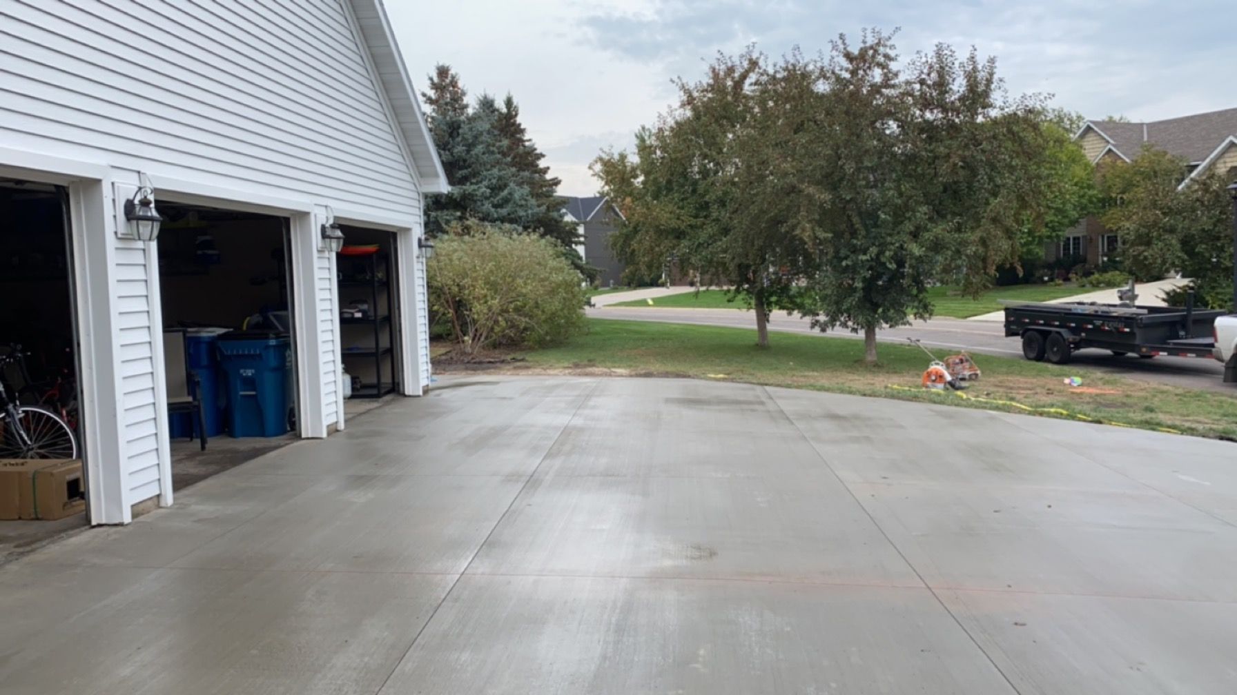 A concrete driveway leading to a garage with a truck parked in front of it.