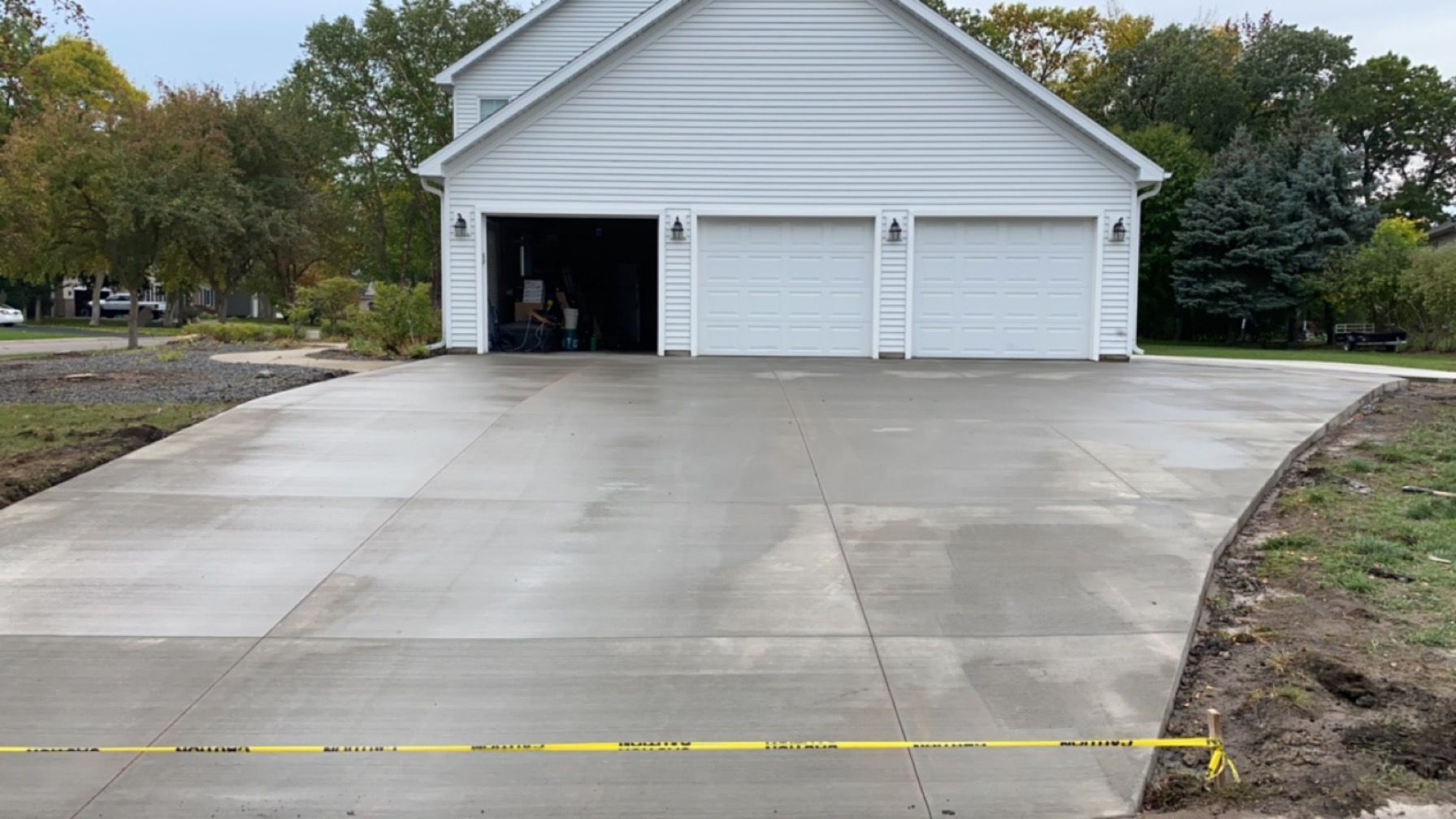 A white garage with a concrete driveway in front of it.