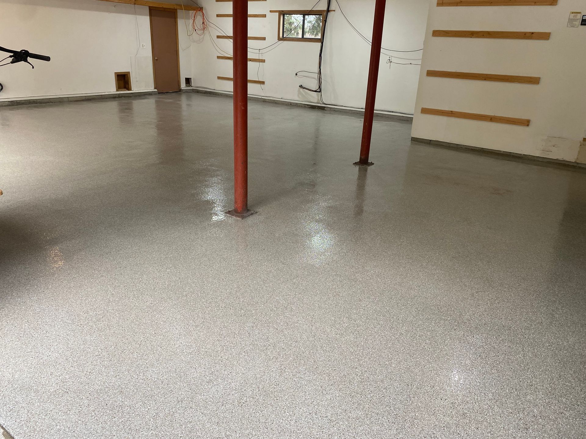 A basement with a concrete floor and a red pole.