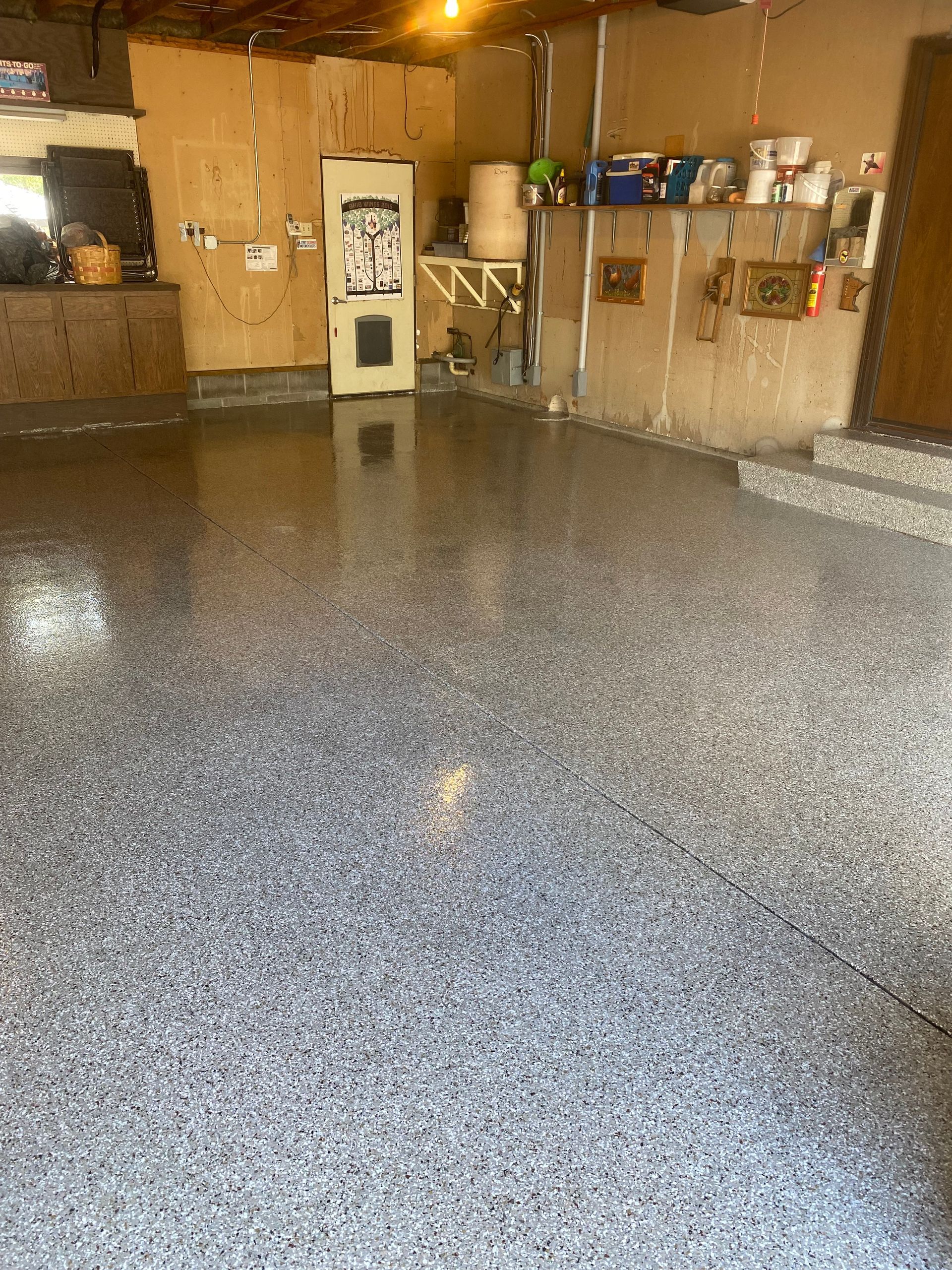 A garage with a gray floor and a refrigerator.