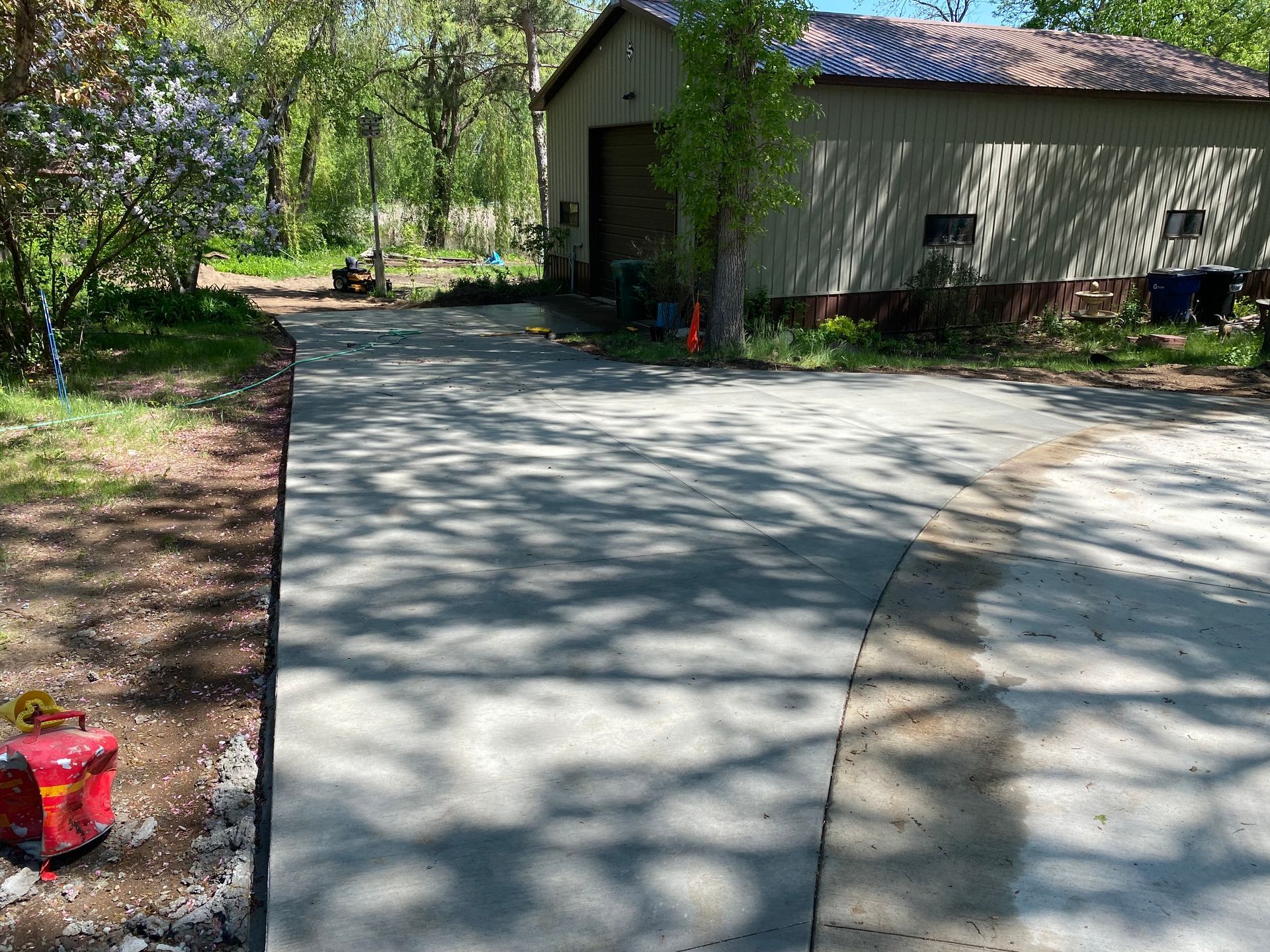 A concrete driveway leading to a garage with trees in the background.