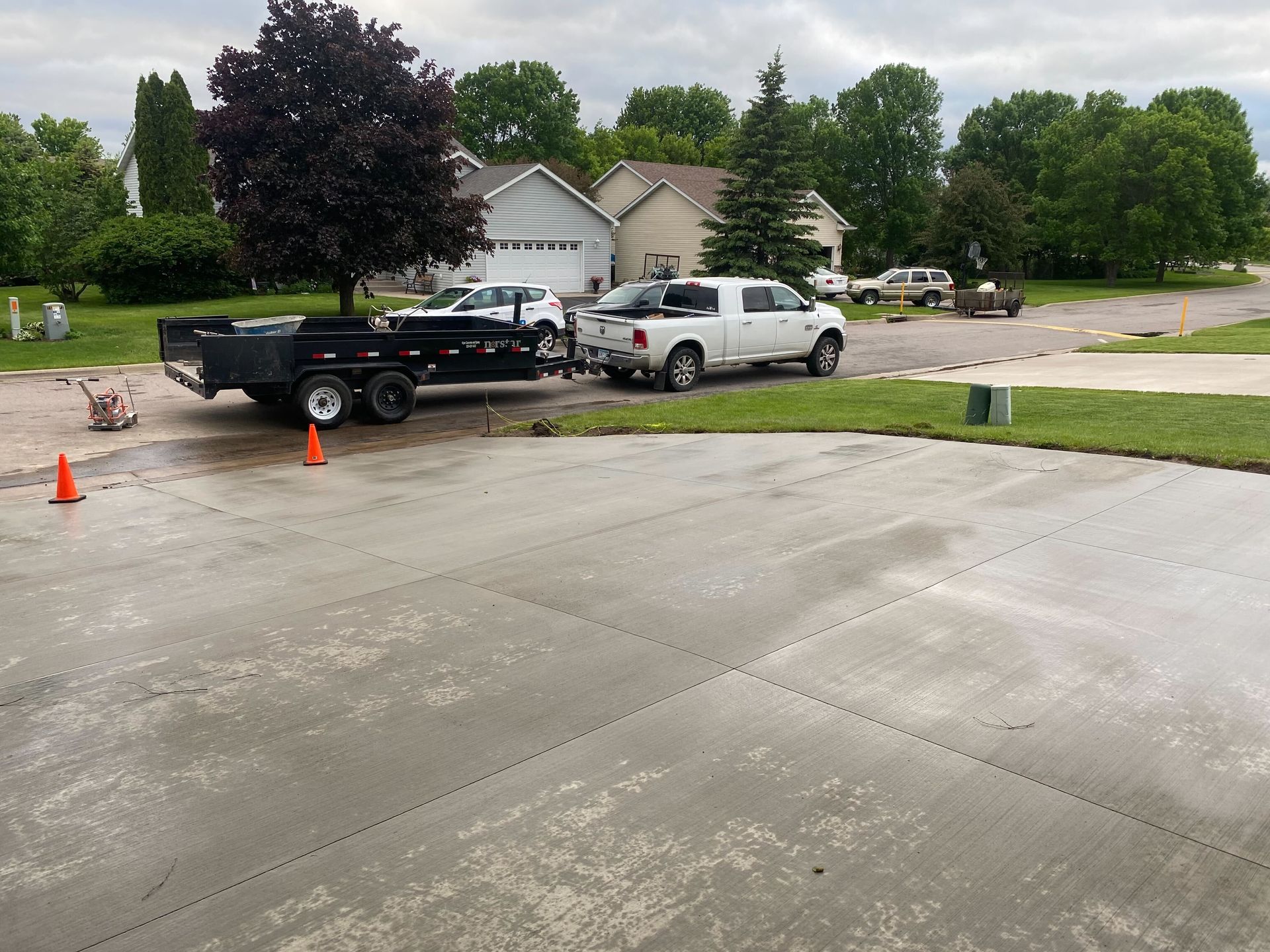 A white truck is towing a trailer in a driveway