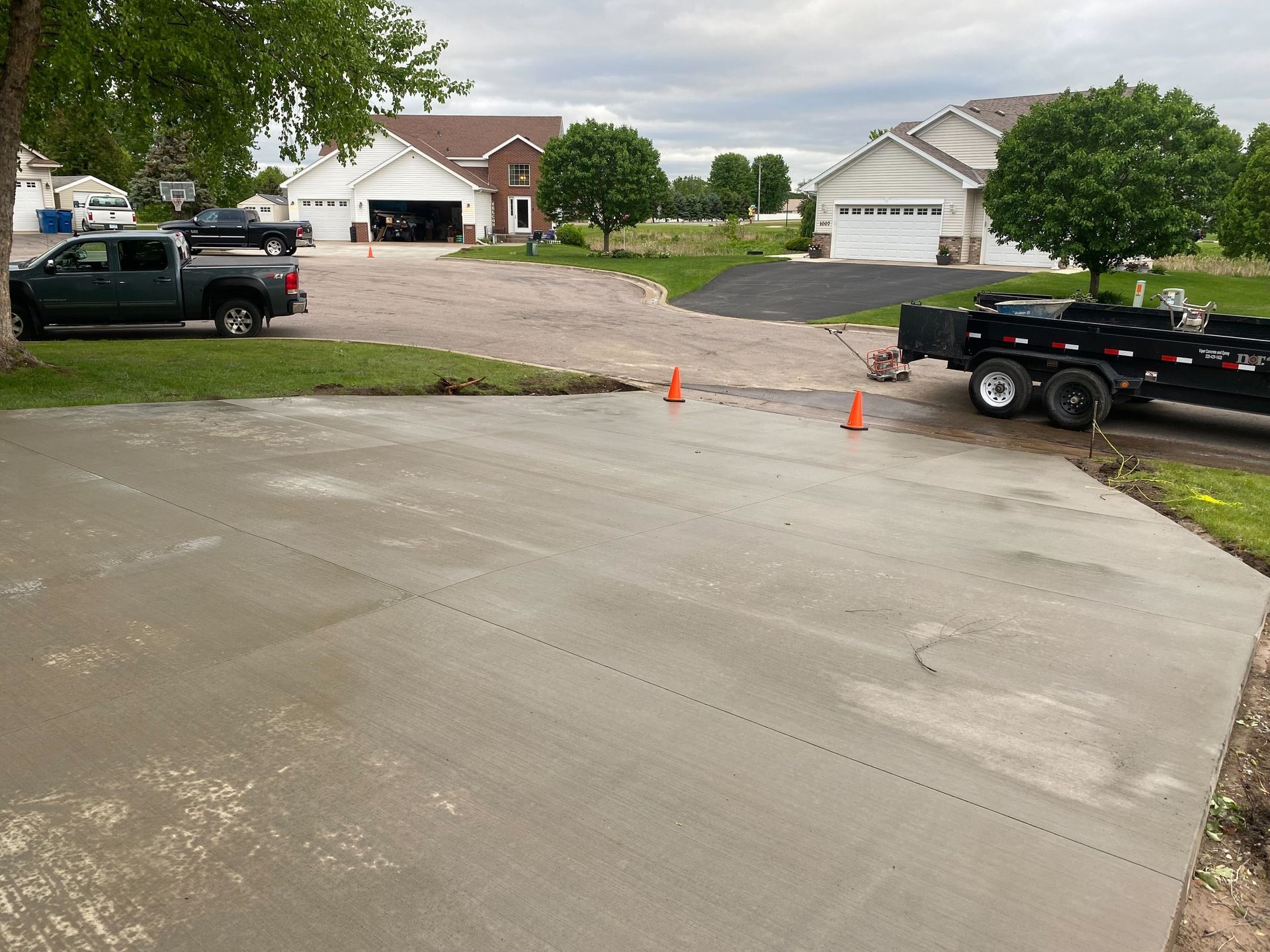 A truck is parked in a driveway next to a trailer.