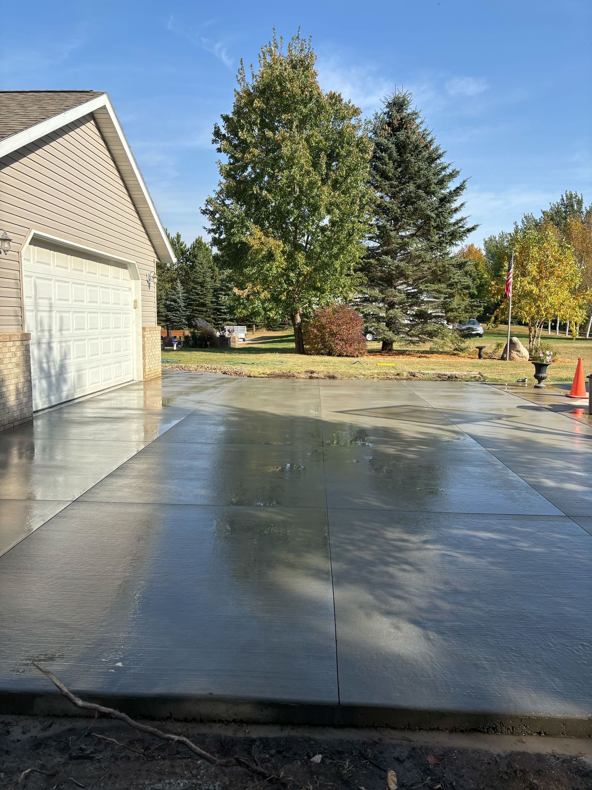 A concrete driveway with a garage in the background and trees in the background.