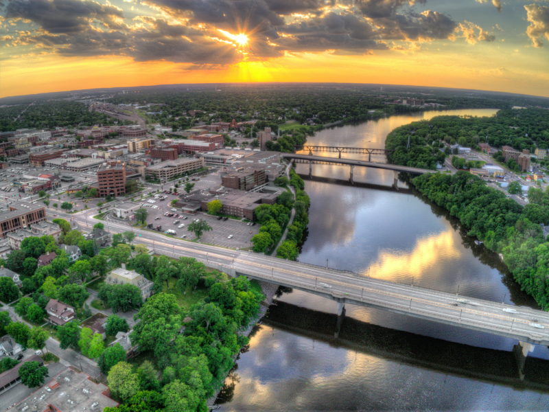 An aerial view of a city with a bridge over a river at sunset.