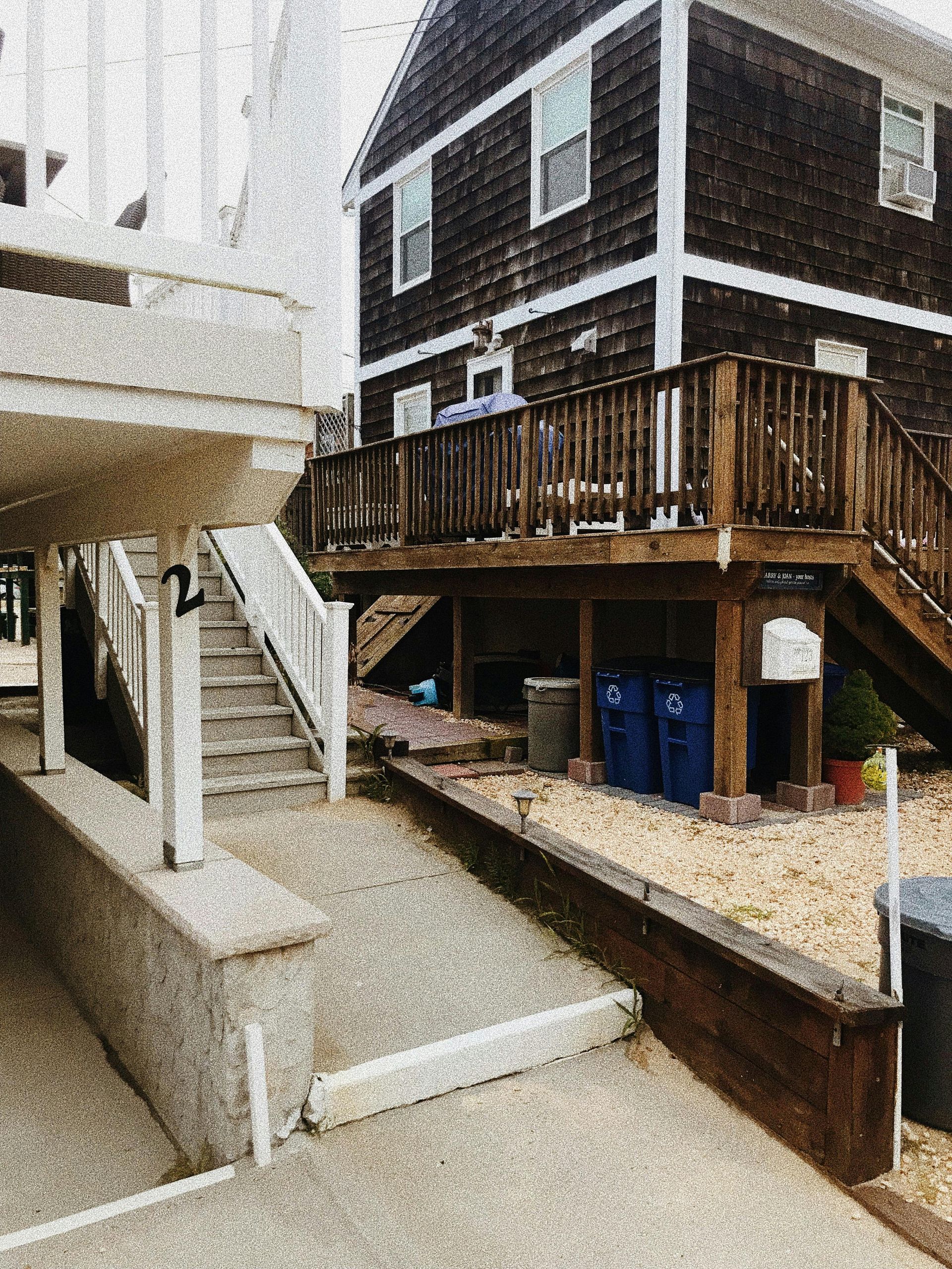 Exterior view of a two-story home with a raised wooden deck and a ramp leading up to the entrance.