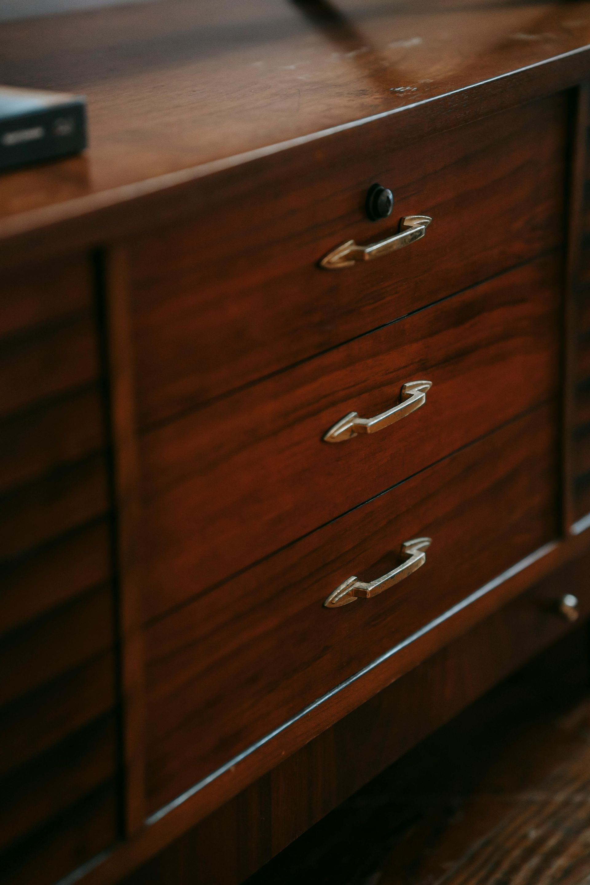 Wooden dresser with three drawers, gold handles, and a lock.
