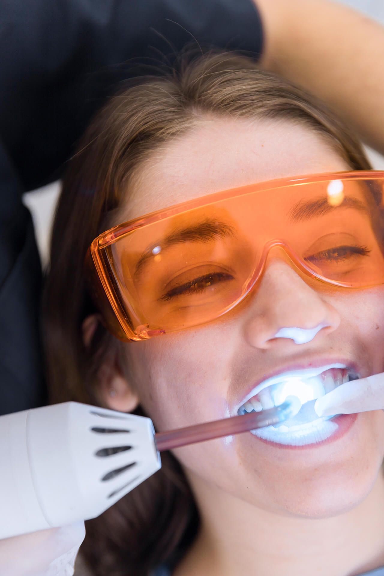 female patient's face going through laser teeth whitening treatment