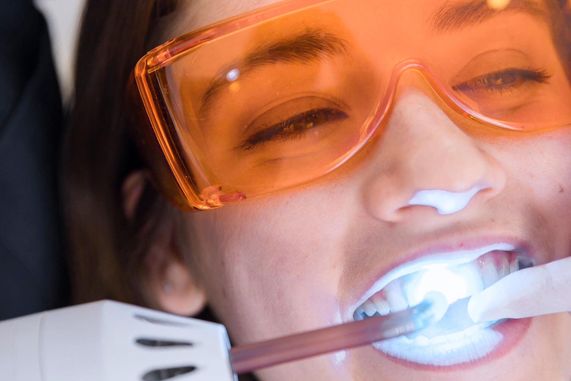 female patient's face going through laser teeth whitening treatment