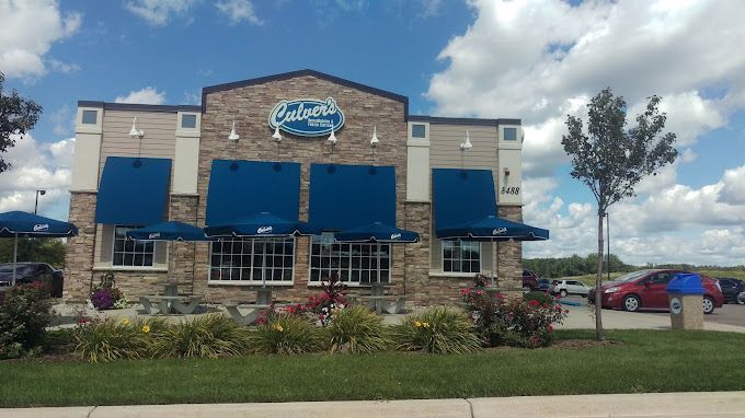 Exterior of a Culvers restaurant with blue awnings and a stone facade under a cloudy sky.