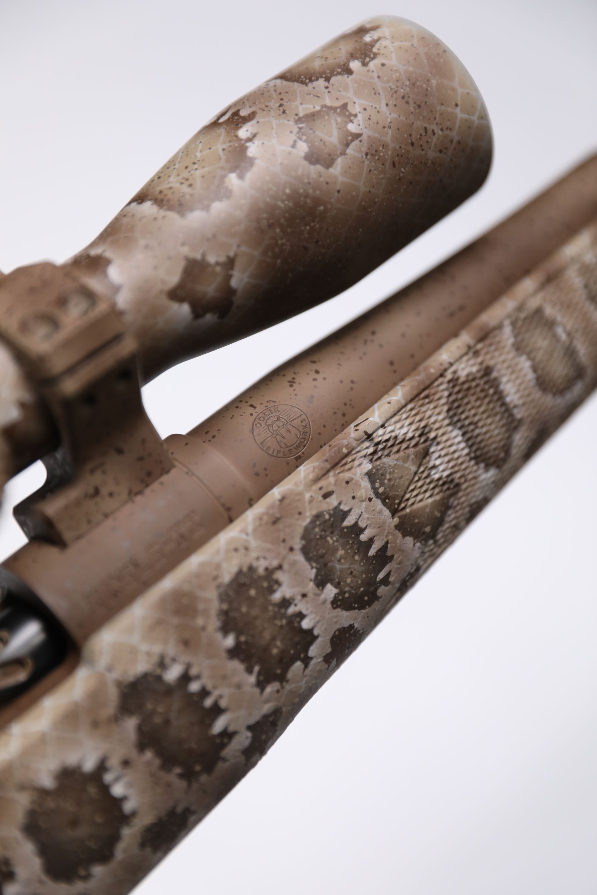 Close-up of a rifle with a snakeskin camouflage pattern on the stock and scope.