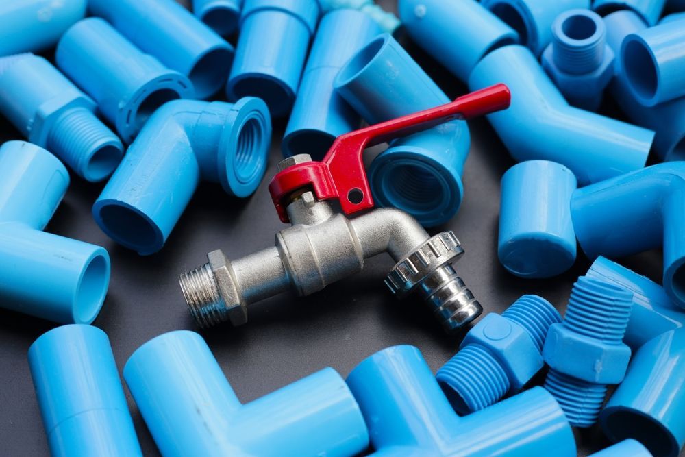 A faucet is sitting on top of a pile of blue plastic pipes.