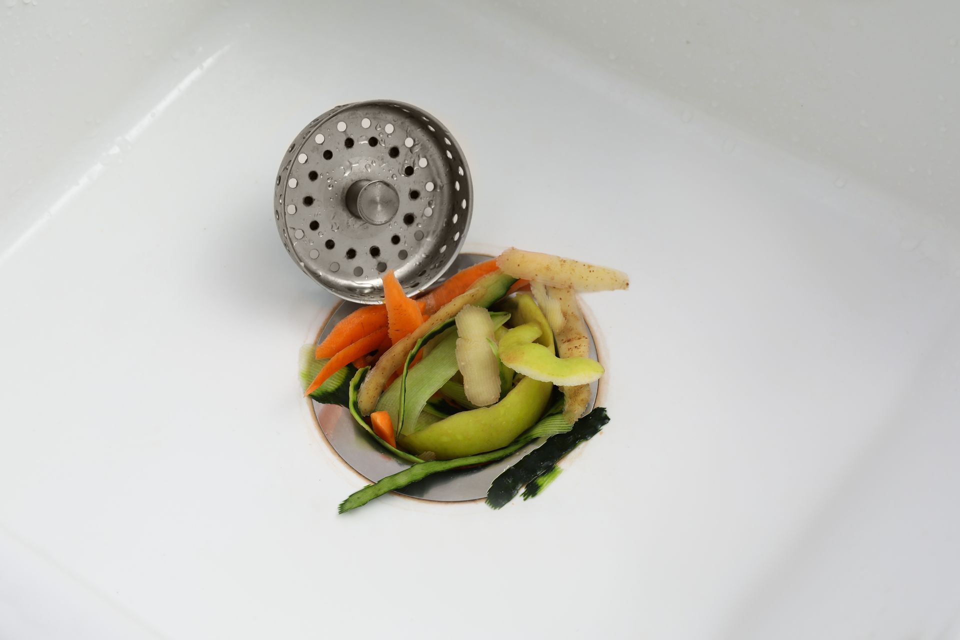 A sink drain with vegetables coming out of it.