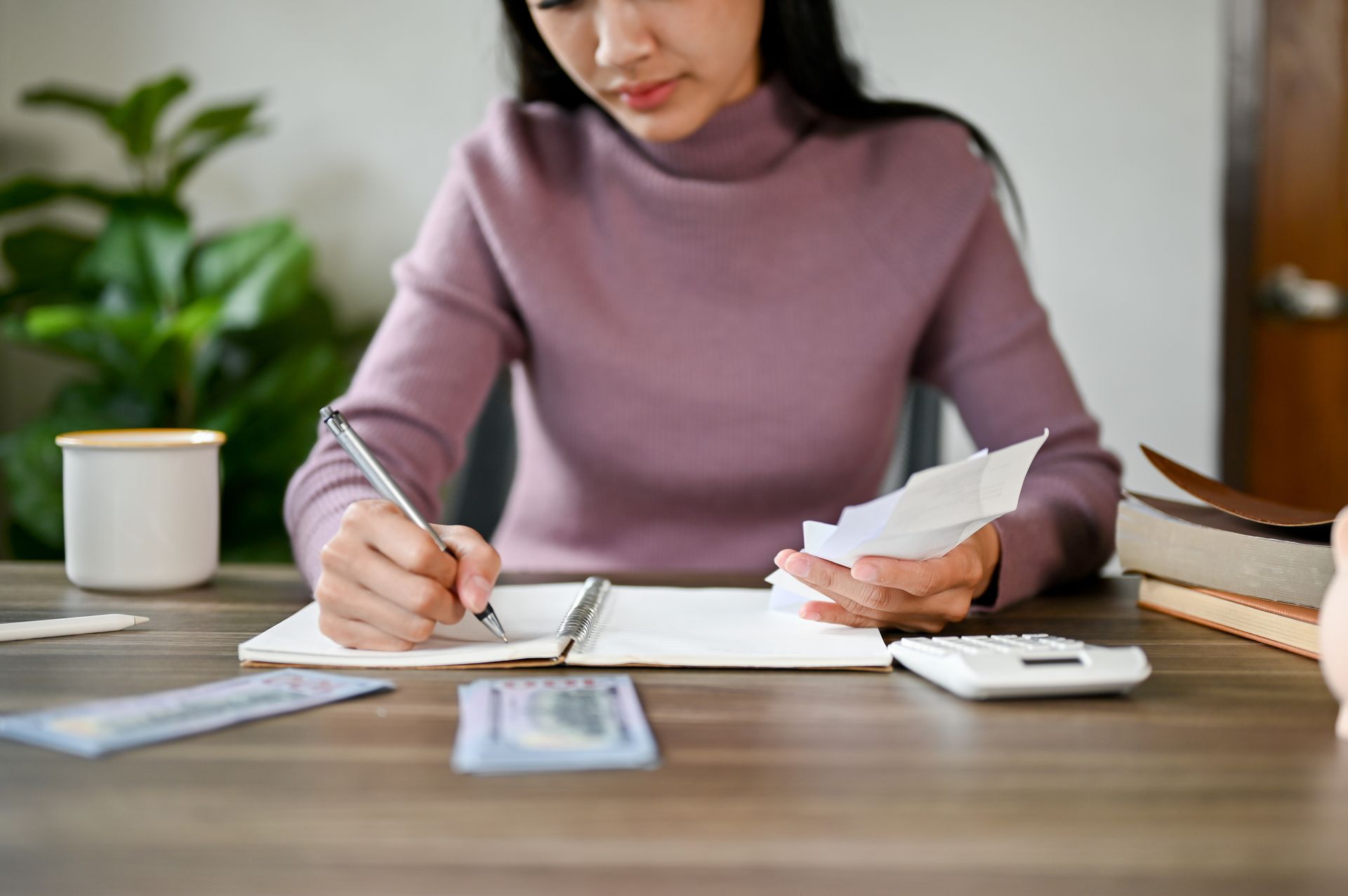 A woman is sitting at a desk writing in a notebook.
