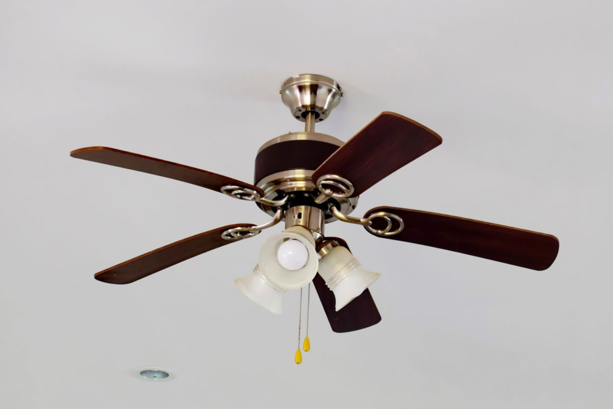 Ceiling fan with brown blades and lights on a white ceiling.