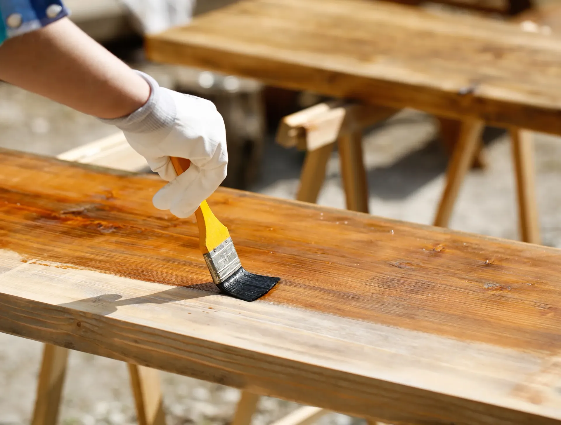 Ellis & Son Painting - A person is painting a piece of wood with a brush.