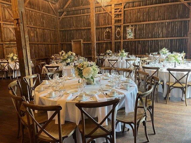 A barn filled with tables and chairs set up for a wedding reception.