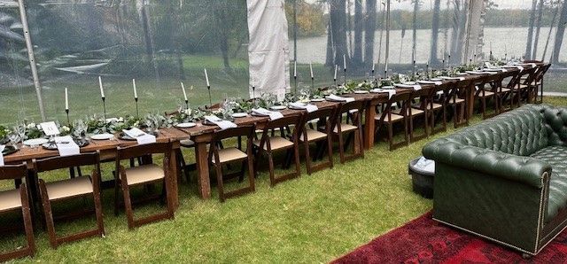 A long table with chairs and a couch under a tent.