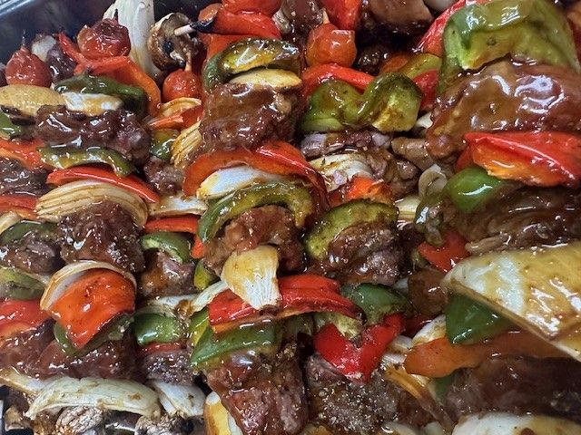 A close up of a plate of food with meat and vegetables on skewers.
