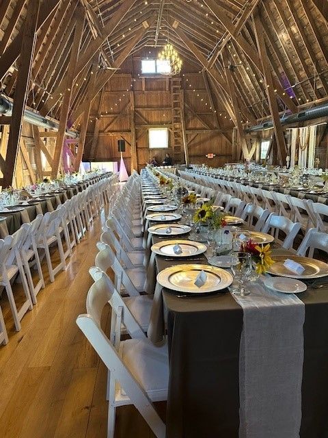 A barn filled with tables and chairs set up for a wedding reception.