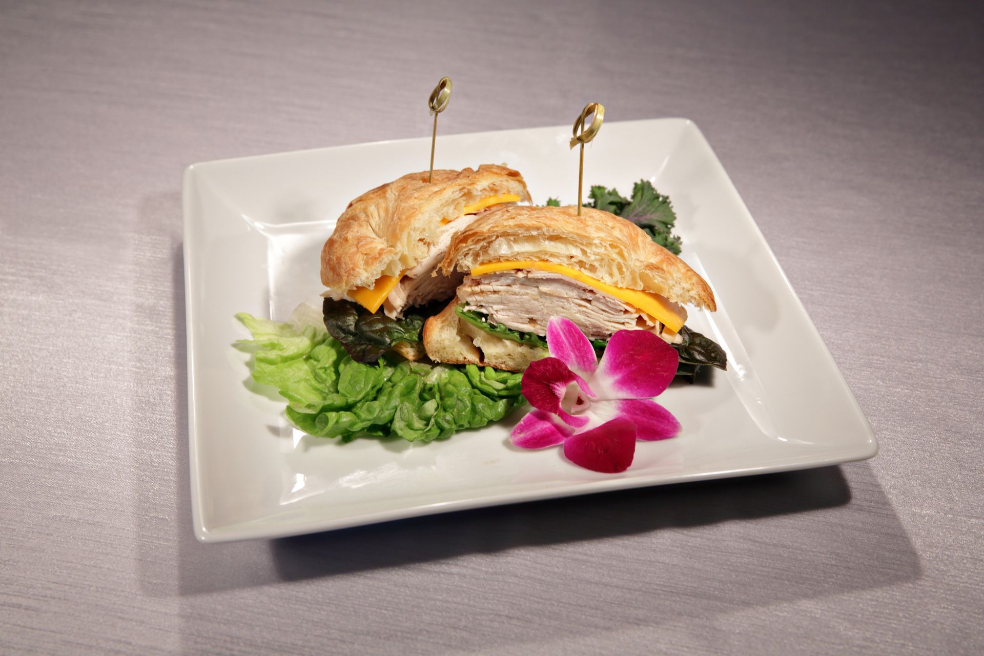 A white plate topped with a sandwich and a flower.