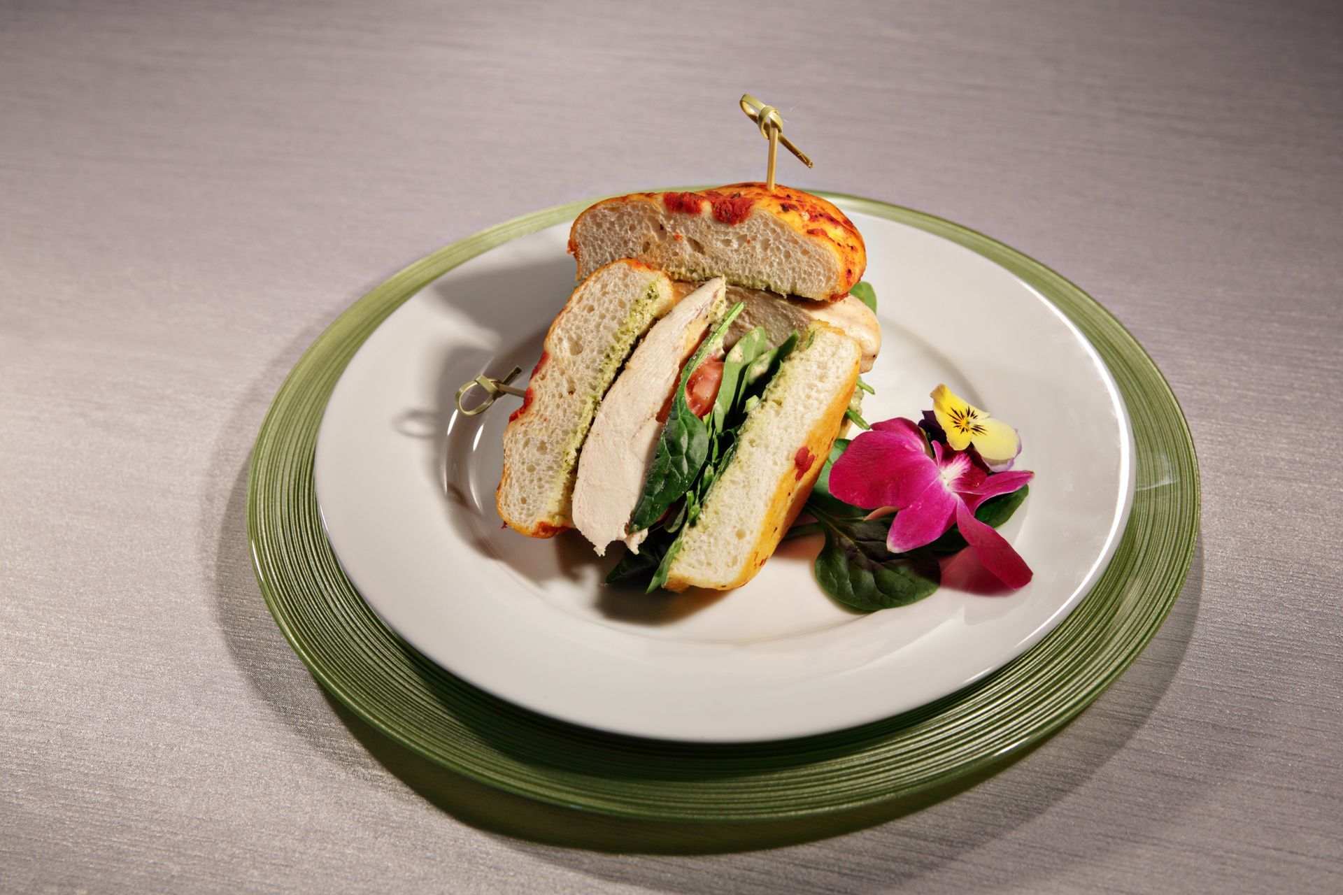 A white plate topped with a sandwich and a flower