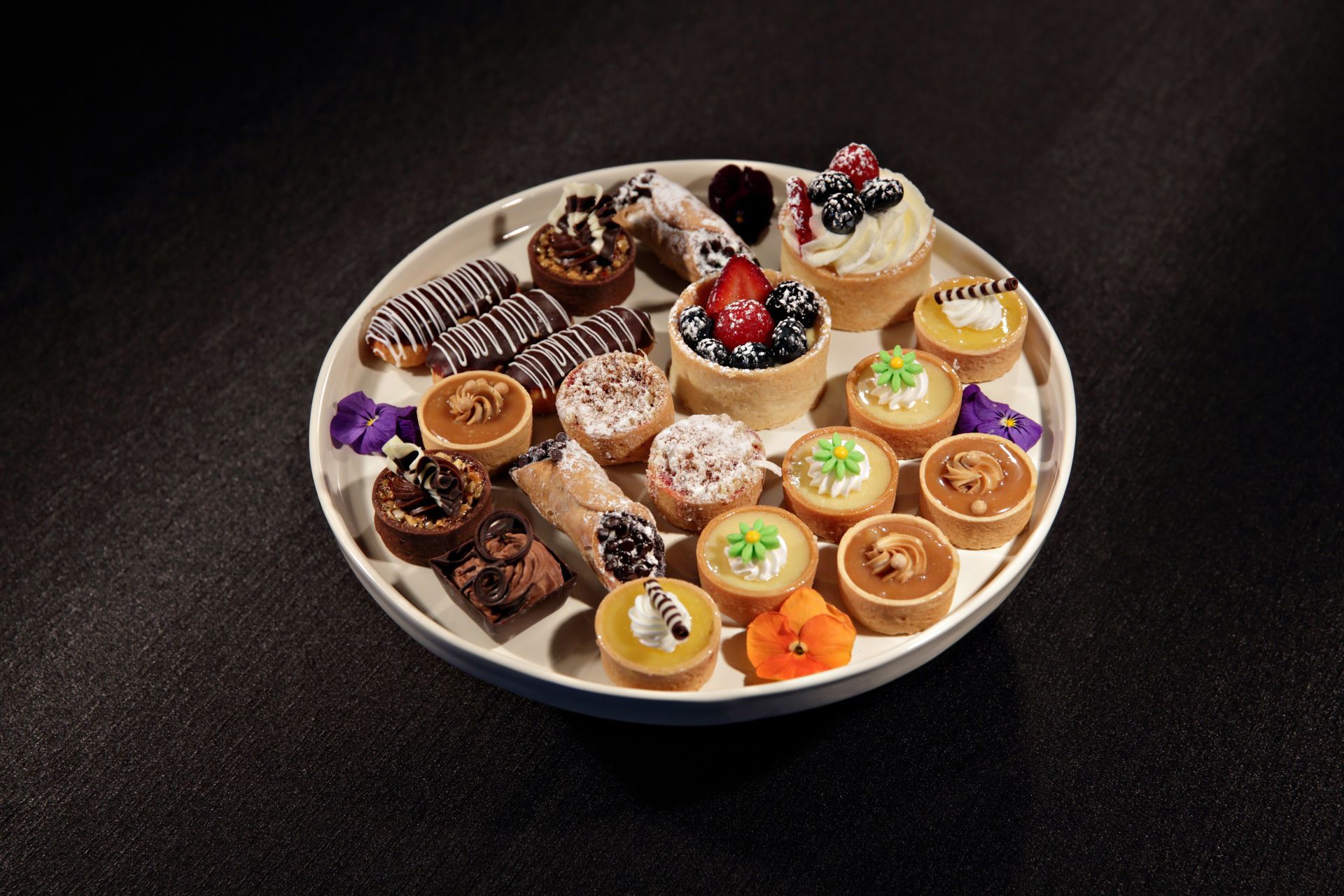 A white plate topped with a variety of desserts on a table.