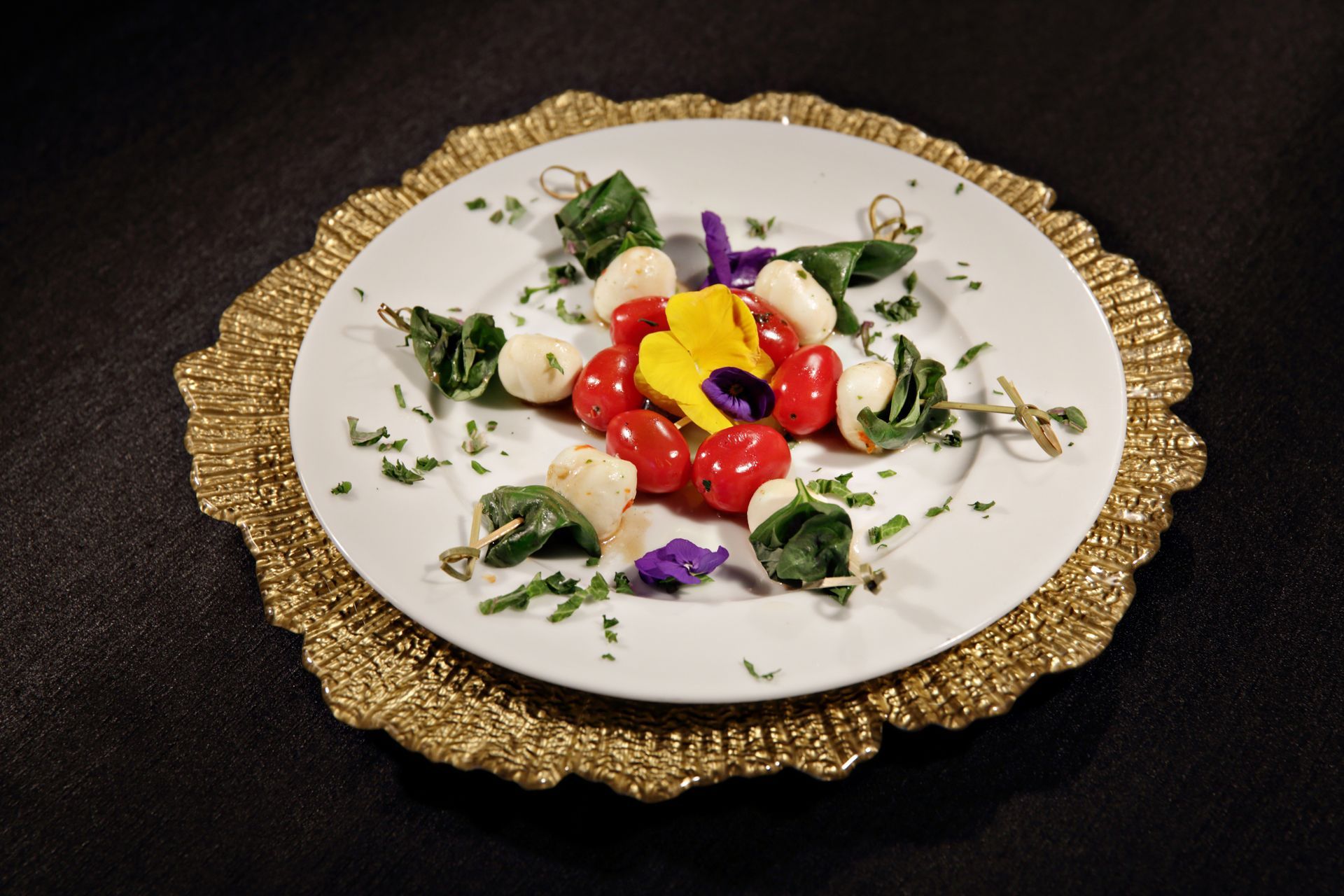 A plate of food with tomatoes and mozzarella on a gold plate