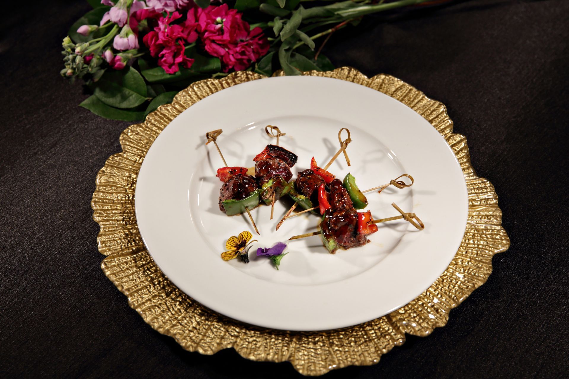 A plate of food on a gold placemat with flowers in the background