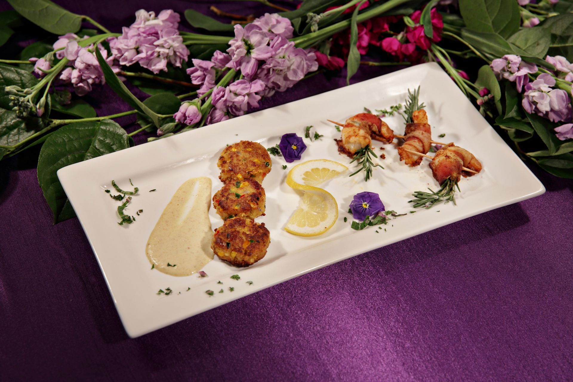 A plate of food with purple flowers in the background