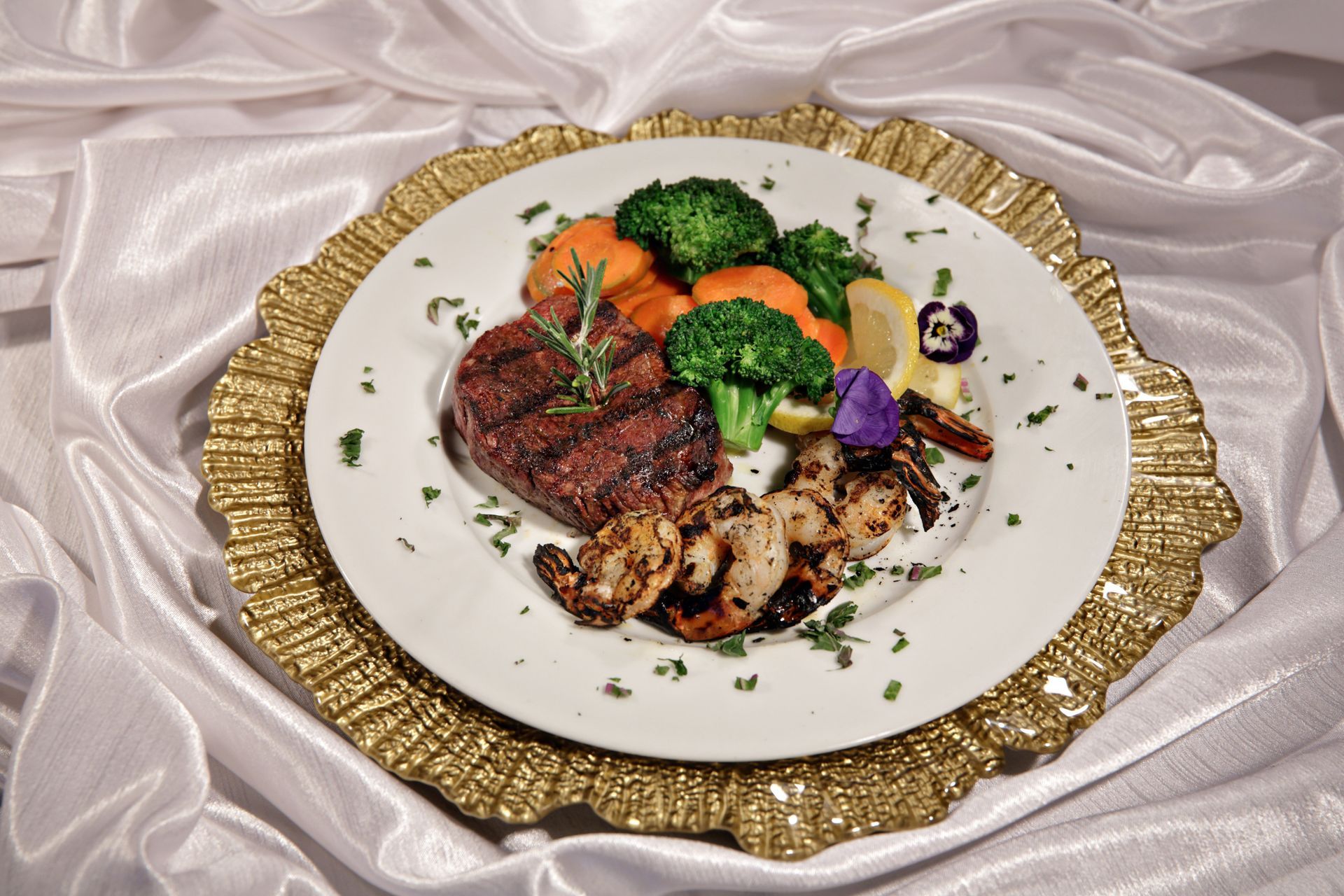A white plate topped with meat and vegetables on a gold plate