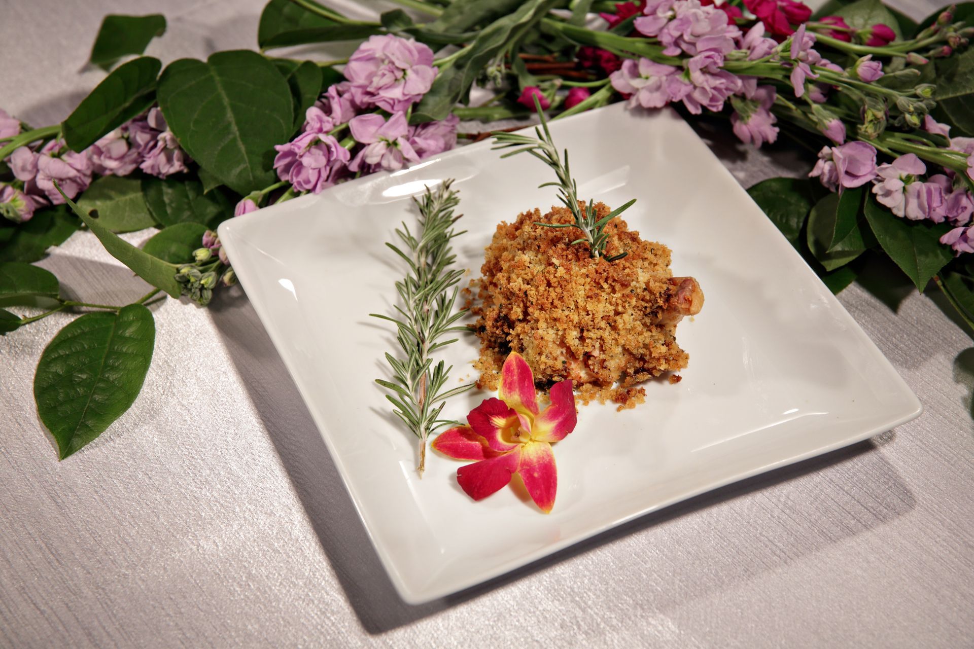 A white plate topped with food and flowers on a table.