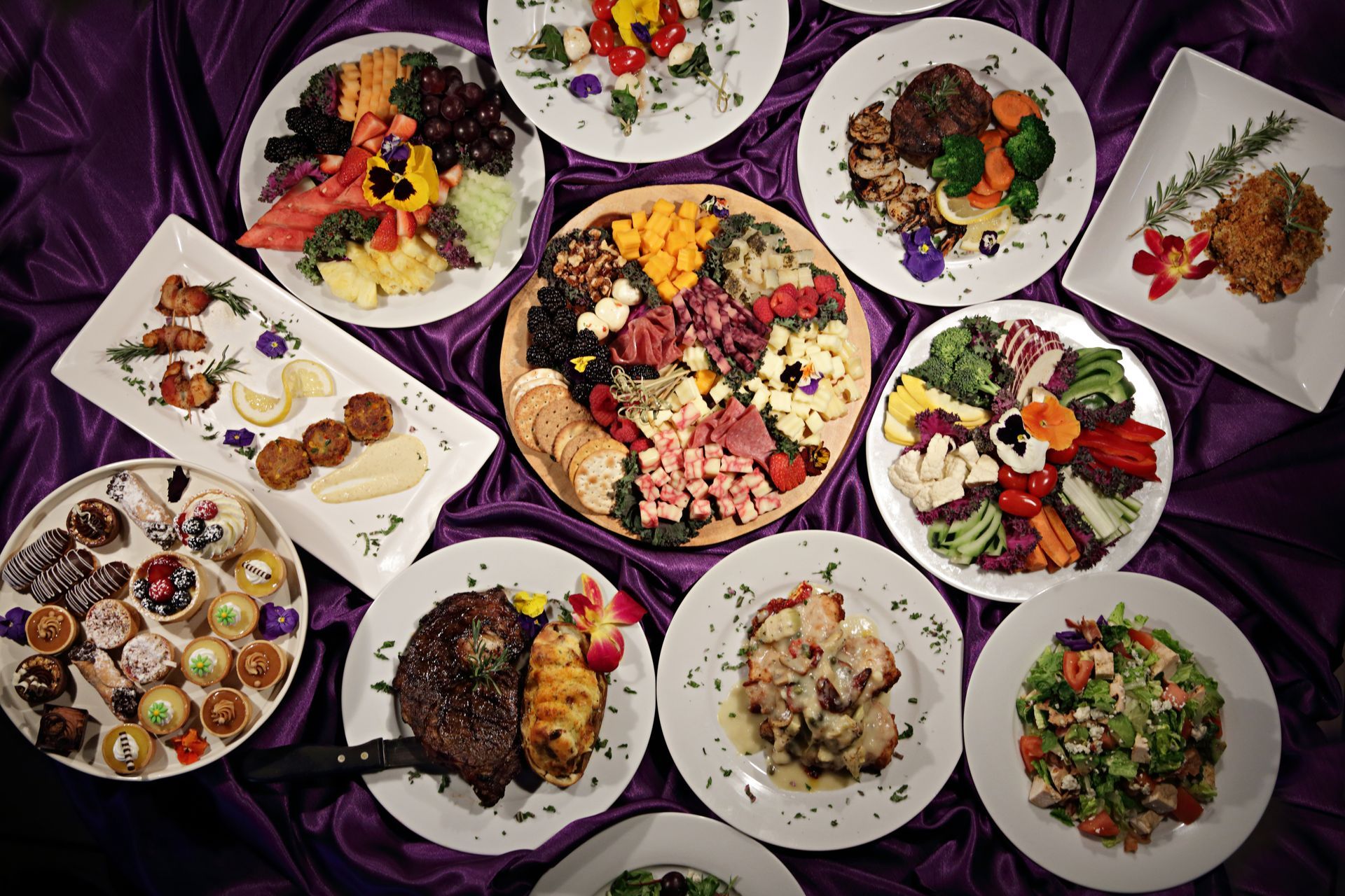 A variety of plates of food on a purple cloth