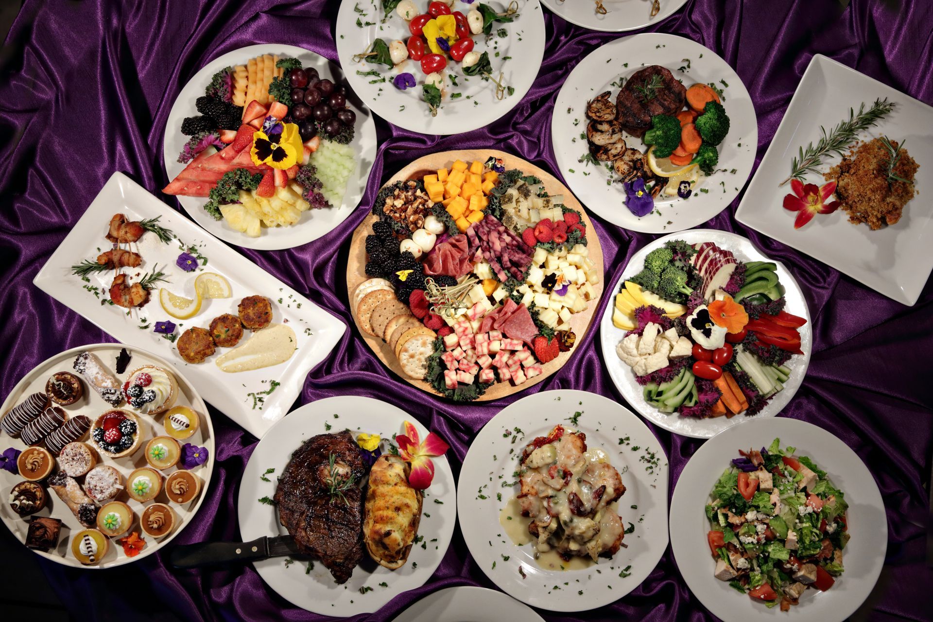 A table topped with plates of food on a purple cloth.