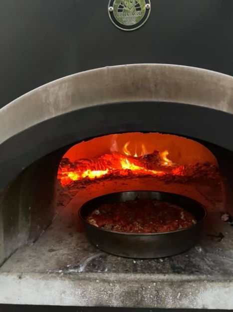 A pizza is being cooked in a pizza oven