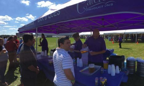 A group of people are standing under a purple tent.