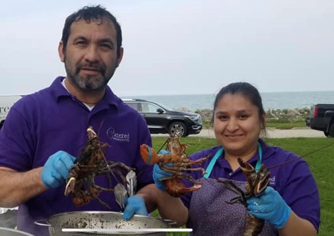 A man and a woman are holding lobsters in their hands
