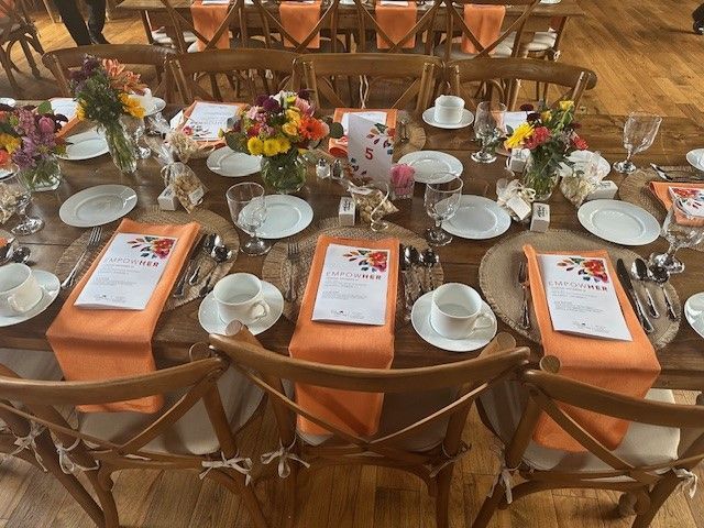 A long table with orange napkins and flowers on it